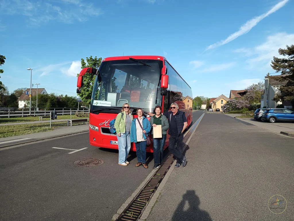 Reisebus der HeimatTouren am Straßenrand, davor die Gruppe