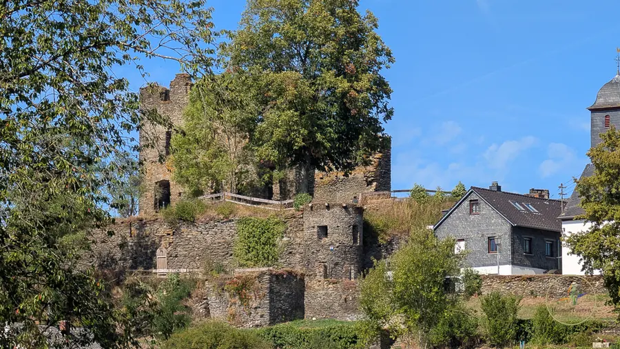 Mauerreste mit Fachwerkhaus im Hintergrund